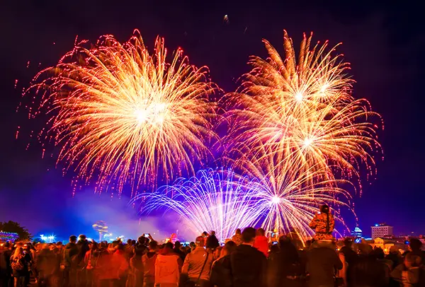 Feu d'artifice avec quatres grosses fusées rouge et une public important